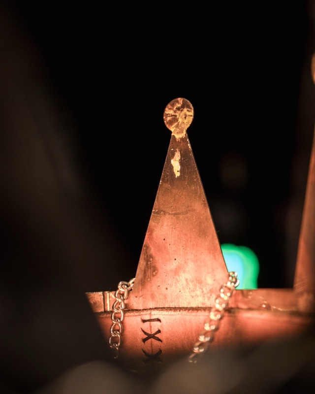 A copper point of the crown above the leather band marked with a Roman numeral