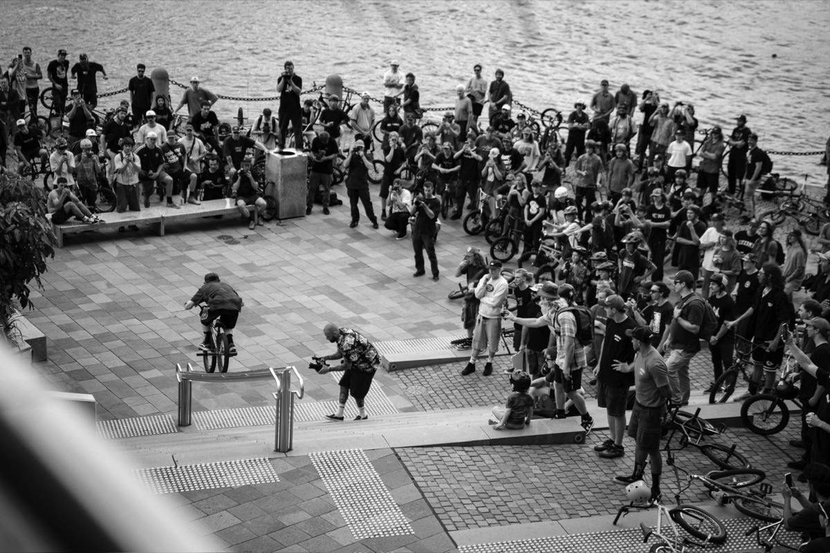Hundreds of riders line a riverside plaza in Brisbane as a rider hops a rail at King Of BNE